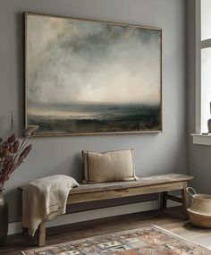 a painting hanging on the wall next to a wooden bench in front of a window