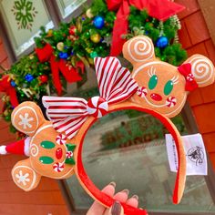 a hand holding up a mickey mouse ears headband with candy canes on it