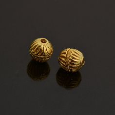 two gold bead caps sitting on top of a black table next to each other