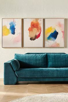 a living room with two paintings on the wall and a couch in front of it