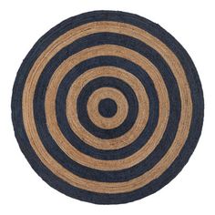 a black and tan area rug with an oval design on the center, in front of a white background