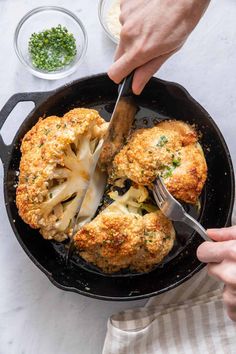 someone is cutting up some food in a skillet with a knife and fork on the side