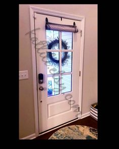 a white front door with a wreath on the window sill and an entry mat