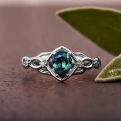 A handmade Celtic style platinum ring set with a beautiful, pear shaped Montana sapphire and small accent diamonds. The center stone is a 5mmX7mm natural Montana teal sapphire of high quality. Please note that the sapphires are natural stones and the exact shade may vary. The smaller stones are natural diamonds with a total carat weight of 0.06ct The ring is made with any of the available metals you select. All of the metals we use are 100% recycled. If you have any questions please feel free to Pear-shaped Topaz Promise Ring With Accent Stones, Pear-shaped Sapphire Diamond Ring, Teardrop Emerald Ring With Diamond Prong Setting, Teardrop Diamond Ring With Accent Stones, Pear-shaped Sapphire Ring With Center Stone, Teardrop Sapphire Ring With Diamond, Teardrop Sapphire Ring With Accent Stones, Moissanite Teardrop Promise Ring, Teardrop Moissanite Promise Ring