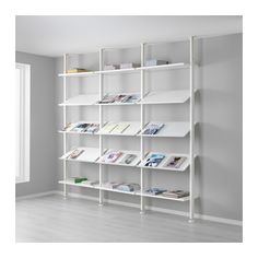 a white shelving unit with books on it in an empty room next to a window