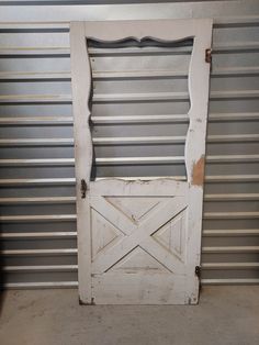 an old white barn door in front of a metal wall