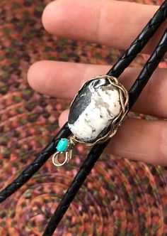 "A very unique bolo slide, completely handmade from high quality stock. Otteson-mined, \"White Buffalo\" Stone & vintage Sleeping Beauty\" turquoise are nestled in a rustic braided setting made of American made Sterling Silver. 3 thick strands of 16 gauge 1/2 round sterling silver wire are freely braided and shaped to create a rustic woven bezel. At the bottom is a classic 6x4mm basket setting. Soldered for strength & durability. On the back, a vintage steel bolo slide accommodates any 4-5mm cor Artisan Bolo Ties With Sliding Knot As Gift, Artisan Bolo Ties With Sliding Knot For Gift, Artisan Bolo Tie With Sliding Knot As Gift, Handmade Bolo Ties As Unique Gifts, Handmade Southwestern Lariat Bolo Tie, Handmade Southwestern Bolo Ties, Handmade Southwestern Turquoise Bolo Ties, Handmade Artisan Turquoise Bolo Ties, Artisan Handmade Turquoise Bolo Ties