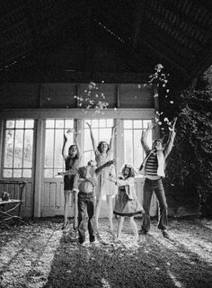 black and white photograph of four people throwing confetti in the air at night