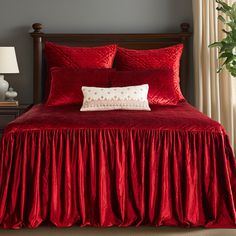 a bed with red bedspread and matching pillows