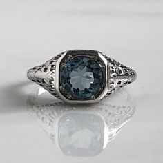 Details: Beautiful Edwardian Aquamarine 18K white gold filigree ring. This ring is very sweet, with delicately detailed filigree with tiny French fleur-de-lis . The aquamarine measures 7.3mm round. The ring is stamped 18K on the inside of the band. Measurements: Ring measures a size 6 1/2 US. It can be re-sized for a fee. Condition: The overall all condition of this ring is very good. Please ask all questions prior to placing an order. Luxury Silver Engraved Filigree Ring, Luxury Engraved Silver Filigree Ring, Elegant Blue Topaz Gemstone Signet Ring, Elegant Blue Topaz Signet Ring With Gemstone, Classic Sterling Silver Intaglio Ring, Elegant White Gold Platinum Signet Ring, Luxury Signet Ring With Intricate Design For Anniversary, Elegant Oval Engraved Ring With Intricate Design, Elegant Engraved 14k White Gold Ring