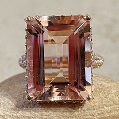 This 10 Carat Morganite Ring is part of our Amara Collection, which is characterized by a gorgeous, genuine gemstone with diamonds studding the hidden halo, prongs, and triple 3/4 eternity shank. Center Stone:  Genuine Peachy Pink Morganite, Emerald Cut, average 16x12mm and 10.50 carats.   Side Stones:  About 140 Diamonds - you choose Lab Grown or Organic - averaging 1.03 carats and F-G, VS2-SI1 in quality. All shapes and sizes and gemstones available upon request. We are a Truly Handmade, Famil Classic Morganite Jewelry With Prong Setting, Exquisite Formal Morganite Ring, Morganite Ring With Diamond Accents, Elegant Morganite Rings With Baguette Cut, Rose Gold Octagon Ring With Prong Setting, Rose Gold Octagon Jewelry With Prong Setting, Exquisite Morganite Rings For Anniversary, Elegant Morganite Jewelry With Accent Stones, Luxury Crystal Ring With Gemstone Accents For Wedding