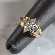 a close up of a ring on a black cloth with white and yellow diamonds in it