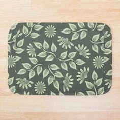 a bath mat with leaves on it sitting on a wooden floor in front of a wall