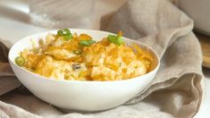 a white bowl filled with macaroni and cheese on top of a cloth covered table