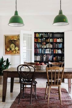 a dining room table with chairs and bookshelves in the background