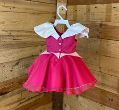 a pink and white dress hanging on a wooden wall