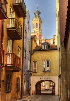 an alley way with buildings and a clock tower in the background