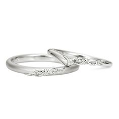 two gold wedding bands with swirl designs on them, one in the shape of an arrow