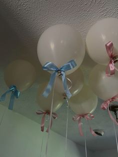 white balloons with blue ribbons hanging from the ceiling