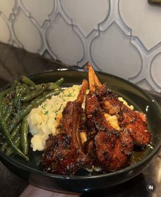 a plate with meat, mashed potatoes and green beans