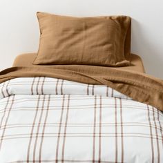 an unmade bed with brown and white checkered comforter on top of it