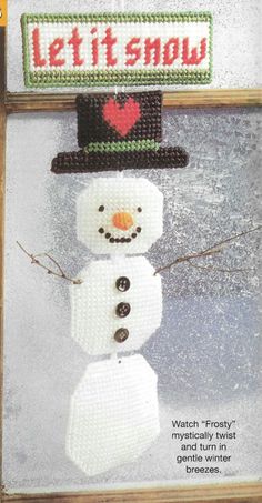 a cross stitch snowman with a sign that says let it snow on the front