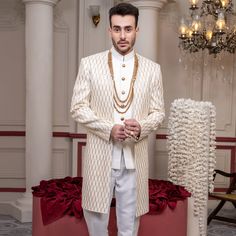 Key Features: Color and Fabric: White Base: The sherwani is primarily white, giving it a classic and sophisticated look. Embroidery: It showcases intricately designed golden embroidery, including a hint of opulence. Design: Open Front: The open-front fashion enhances the overall silhouette and allows for layering. V-Neck: The V-neck layout adds beauty and frames the face fantastically. Waistcoat: White Waistcoat: Complementing the sherwani, the waistcoat is also white, ensuring a cohesive look. White Sherwani, White Waistcoat, Golden Embroidery, Gold Buttons, Formal Occasion, Neck Designs, Front Open, The Face, Layering