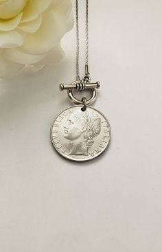 This vintage coin necklace will soon become a favorite go-to necklace. It features an Italian pre-euro silver-tone coin that dangles from an 18" stainless steel chain with a front toggle clasp. Your choice between a 50-lire (24mm or 7/8" in diameter) coin or a 100-lire (27mm or 1" in diameter) coin. Just a beautiful Italian heritage gift! Welcome to Recycled Finery!  I repurpose old jewelry, coins, beads, vintage buttons, watch parts, and charms into new jewelry.  My ever-growing collection of these materials comes from estate sales, rummage sales, antique and thrift stores, and family and friends' collections they no longer need or want. I have fun putting these new pieces together and hope you will find them fun to wear and as unique gifts for your loved ones.     Please note: Because my Vintage Metal Medallion Necklace With Coin Pendant, Vintage Charm Medallion Necklace Gift, Gift Medallion Necklace With Vintage Charm, Round Medallion Necklace With Vintage Charm As A Gift, Vintage Metal Coin Necklace With Round Pendant, Antique Nickel-free Medallion Necklace As Gift, Silver Necklaces With Coin Pendant For Vintage Collection, Vintage Round Coin Necklace With Adjustable Chain, Vintage Antique Silver Jewelry With Coin Pendant