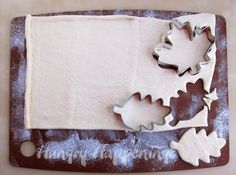 some cookie cutters are laying on top of a baking sheet that is shaped like leaves