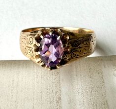 "a gorgeous antique gold ring with an amethyst stone.  the amethyst is a new stone, a replacement for the original amethyst which was quite chipped.  also at least one prong has been replaced, but very hard to tell which one.  this ring is a Victorian era piece, it's been around the block.  it has some markings but i am clueless as to their meaning, and some scratch marks on the inner band, likely where it was tested for gold content, which, by the way, is 10k.  wonderful design work on the side Antique Gold Ring, Antique Amethyst Ring, Antique Gold Rings, Gold Amethyst Ring, Ring Antique, Clueless, Amethyst Stone, Wide Bands, Amethyst Ring