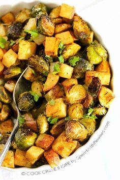 a bowl filled with potatoes and brussel sprouts next to a spoon