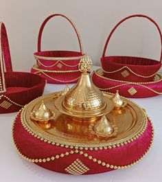 three red baskets with gold decorations on them and one has a basket in the middle