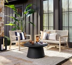 two chairs and a coffee table on a patio with a potted plant in the corner