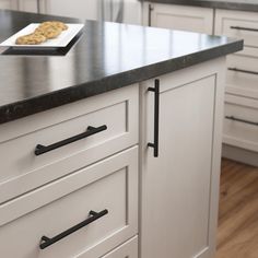 a kitchen with white cabinets, black counter tops and an island that has cookies on it