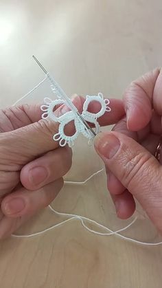 two hands are working on an object that looks like a butterfly