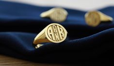 three gold monogrammed rings sitting on top of a blue cloth