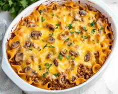 a casserole dish with meat, cheese and mushrooms in it on a table