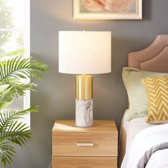 a bedroom with a bed, nightstand and painting on the wall above it that has a plant next to it