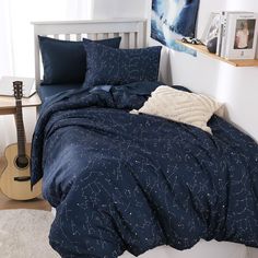 a bed with blue comforters and pillows in a bedroom next to a guitar on the floor