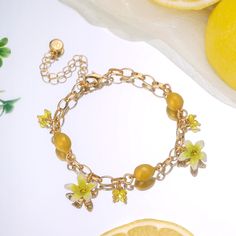 Experience the refreshing and invigorating essence of the Lemon Bracelet. Embrace nature with its sweet, juicy lemon design that evokes memories of sunny days, tropical vacations, and cool breezes. Let its vibrant flowers and fruit design add a touch of summer zeal to your style. Embrace the zesty spirit of summer and Celebrate the luxurious pleasures of nature's bounty with this delightful Lemon Bracelet! DETAILS Plating: 18K Gold Materials: 18K Gold on Brass, Enamel, Cubic Zirconia Measurement Elegant Beach Bracelets For Spring, Yellow Beach Jewelry For Spring, Yellow Jewelry For Spring Beach Occasion, Dainty Beach Jewelry For Spring, Yellow Jewelry For Beach In Spring, Yellow Jewelry For Beach Wear In Spring, Elegant Spring Beach Bracelets, Yellow Jewelry For Beach During Spring, Yellow Bracelets For Summer Vacation