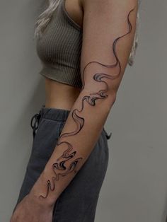 813691ac6d5437ef1b851a044b01746e Woman with a wavy line tattoo on her arm, wearing a green crop top and gray pants. Modern minimalist tattoo design. | Sky Rye Design Swirly Tattoo, Minimalist Tattoo Design, Left Arm Tattoos, Empowering Tattoos, Sunflower Tattoo Sleeve, Arm Sleeve Tattoos For Women, Uñas Ideas