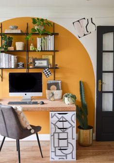 a desk with a computer on top of it next to a potted cacti