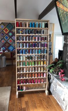 a shelf filled with lots of spools of thread next to a fire place