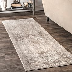 a living room area with a couch, coffee table and rug on the hardwood floor