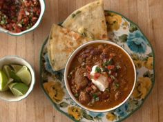 a bowl of chili, tortilla chips and salsa on a floral plate with flowers