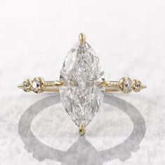 a pear shaped diamond ring with three small diamonds on the band and an oval center stone