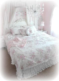 a white bed with pink flowers on it and a chandelier hanging from the ceiling