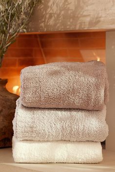 three towels stacked on top of each other in front of a fireplace with a potted plant