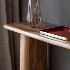 a wooden table with a red tray and vase on it