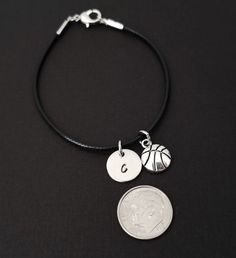 "Personalized Waxed Cord Bracelet! A Basketball charm on a black waxed cord makes the perfect gift for you or your best friend. The basketball charm is made from zinc alloy and measures 13 mm by 10 mm. The charm is not reversible. The basketball bracelet is a waxed braided rope and measures 7.25\" with a 1-2\" extender (see last picture). The lobster clasp is zinc alloy. The black cord bracelet can be personalized with a .5\" silver plated disc stamped with the initial of your choice. Each perso Adjustable Black Bracelets With Charms, Adjustable Nickel-free Black Charm Bracelet, Nickel-free Black Charm Bracelet For Gift, Nickel-free Black Charm Bracelet As Gift, Black Waxed Cord Jewelry For Friendship, Nickel-free Black Charm Bracelet, Black Nickel-free Charm Bracelet, Gift Leather Bracelet With Adjustable Waxed Cord, Adjustable Nickel-free Bracelets With Waxed Cord